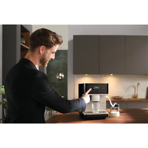 Miele CM6360 Coffee Machines Obsidian Black / Clean Steel Metallic - Person making coffee with machine in kitchen shot
